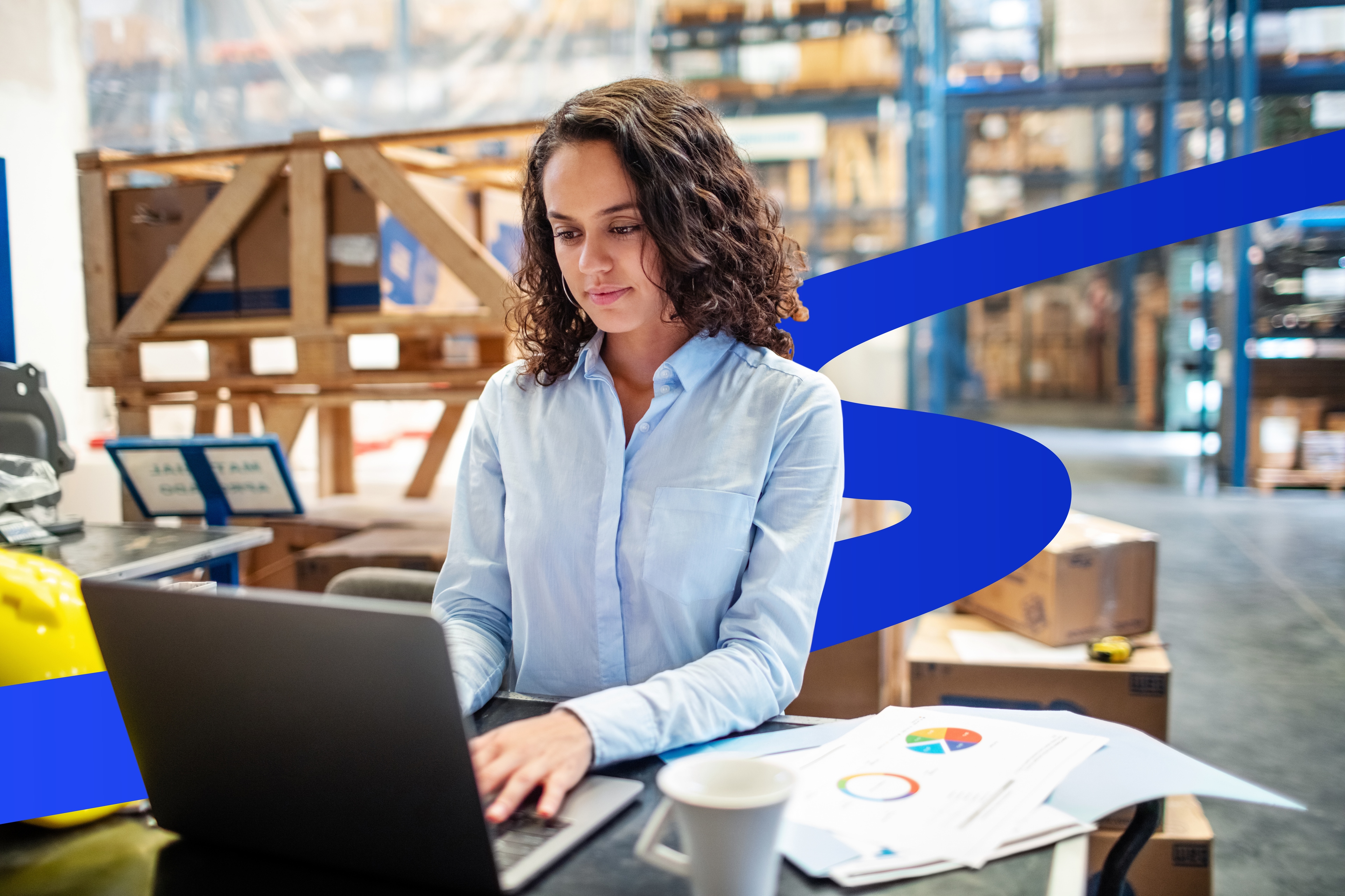 Businesswoman updating stocks on laptop at warehouse